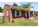 Side view of brick home featuring fenced yard, manicured lawn and cozy front porch with flower baskets at 2719 S Nc 87, Graham, NC 27253