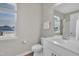 Bright bathroom with a modern vanity, toilet, and a window providing natural light and neighborhood views at 3313 Brunot St, New Hill, NC 27562