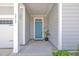 Charming covered front porch with light gray siding, white trim, and a vibrant turquoise front door at 3313 Brunot St, New Hill, NC 27562