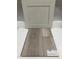 Close-up of Shaw luxury vinyl flooring in Lighthouse color, paired with a cabinet door sample at 351 Chesapeake Cmns St # 111, Garner, NC 27529