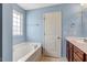 Light-filled bathroom features a soaking tub under the window and modern fixtures at 4109 Massey Preserve Trl, Raleigh, NC 27616