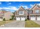 Brick townhome featuring a two-car garage, manicured lawn, and blue sky backdrop at 416 Durants Neck Ln, Morrisville, NC 27560