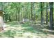 A backyard with an outbuilding shed surrounded by mature trees and green grass at 4221 River Run Dr, Sanford, NC 27332
