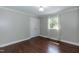 An empty bedroom with hardwood floors, gray walls, a window with white trim and a double door closet at 4221 River Run Dr, Sanford, NC 27332