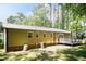 Exterior of home with metal roof, yellow siding and brick foundation, deck and lush green yard at 4221 River Run Dr, Sanford, NC 27332