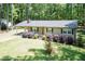 Inviting single-story home with a metal roof, covered carport, and landscaped yard, nestled among mature trees at 4221 River Run Dr, Sanford, NC 27332