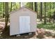 An outdoor backyard shed for storage with a single door surrounded by a wooded area at 4221 River Run Dr, Sanford, NC 27332