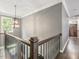 Hallway with wood railing offers an overview of the first floor, accented by a decorative light fixture at 445 Ridge Springs Dr, Chapel Hill, NC 27516
