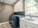 Modern laundry room with front load washer and dryer, white cabinets, and a window at 445 Ridge Springs Dr, Chapel Hill, NC 27516