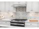 Close-up of a kitchen featuring stainless steel appliances, white cabinets and a mosaic backsplash at 488 Freedom Trail Dr, Angier, NC 27592