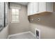 Neutral-toned laundry room with upper cabinets, window with patterned valence, and tile flooring at 488 Freedom Trail Dr, Angier, NC 27592