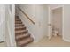Carpeted staircase with a wooden handrail next to a door, and an open bathroom at 509 Darby Glen Ln, Durham, NC 27713