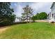 Spacious backyard with green grass, bordered by a wood fence, and neighboring homes in the distance at 5416 Whisperwood Dr, Durham, NC 27713
