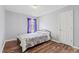 Cozy bedroom featuring wood floors, a comfortable bed, and a window with purple curtains at 5416 Whisperwood Dr, Durham, NC 27713