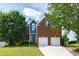 Inviting two-story brick home with a well-manicured lawn, two-car garage, and blue accents at 5416 Whisperwood Dr, Durham, NC 27713
