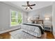 Sunlit bedroom featuring hardwood floors, a ceiling fan, and a large window at 7116 Dumfries Ln, Chapel Hill, NC 27514