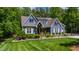 Beautifully landscaped home exterior with lush green lawn, shrubs, and charming architectural details at 7116 Dumfries Ln, Chapel Hill, NC 27514