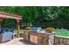 A built-in stone grill area and pergola for outdoor dining or lounging creates an inviting backyard retreat at 7116 Dumfries Ln, Chapel Hill, NC 27514