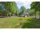 Spacious backyard with green lawn, firepit, mature trees, and pool at 7824 Hemlock Ct, Raleigh, NC 27615