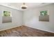 Clean bedroom featuring new hardwood flooring, neutral paint, and natural lighting with dual windows at 7824 Hemlock Ct, Raleigh, NC 27615