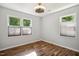 Bedroom with hardwood floors, ceiling fan, and two large windows with shades at 7824 Hemlock Ct, Raleigh, NC 27615