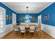 Elegant dining room with bright blue walls, wainscoting, and a modern chandelier over the wooden table at 905 Neuse Ridge Dr, Clayton, NC 27527