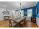 Bright dining area with wooden table, six chairs, modern light fixture, and blue accent wall at 905 Neuse Ridge Dr, Clayton, NC 27527