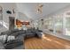 Bright living room with wood floors, large windows, modern gray sectional, and access to kitchen at 905 Neuse Ridge Dr, Clayton, NC 27527