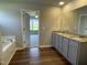 Bright bathroom featuring dual sinks, granite countertops, a tub, and an open doorway at 94 Starry Sky Dr, Benson, NC 27504