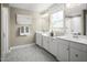 Well-lit bathroom with double vanity, white cabinets, gray tile floor, and glass shower at 1012 Country Pasture Cv, Wendell, NC 27591