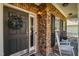 Close-up of a stone-accented front porch with a wreath, rocking chair, and a stylish front door at 1028 Bellenden Dr, Durham, NC 27713