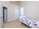 This bedroom features a twin bed with patterned cover, neutral carpet, and a large window at 10529 Sablewood Dr # 116, Raleigh, NC 27617