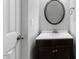 Cozy powder room with modern vanity, dark cabinets, updated fixtures, and round mirror at 107 Caraleigh Ct, Morrisville, NC 27560