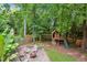 Backyard features a stone patio with seating, fire pit, custom built treehouse and swing set, great for entertaining at 1102 Whiston Dr, Apex, NC 27502