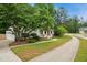 Suburban home featuring a lush front yard, a sidewalk, mature trees, and a charming covered front porch at 1102 Whiston Dr, Apex, NC 27502