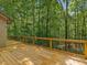 Expansive deck with wood railing showcases scenic views of the surrounding lush greenery and towering trees at 120 Spring Hollow Ln, Cary, NC 27518