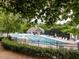 Community pool area featuring a swimming pool, lounge chairs, and a pool house, all enclosed by a black fence at 120 Spring Hollow Ln, Cary, NC 27518
