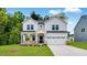 Two-story home with white siding, a covered porch, and an attached two-car garage on a green lawn at 174 Hickory Grove Dr, Sanford, NC 27330