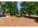 Landscaped backyard featuring a wooden gazebo, deck, mature trees, and pine straw ground cover at 1816 Albacore Ln, Raleigh, NC 27612