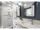 Bathroom featuring double sink vanity, granite counters, framed mirrors, and tiled shower at 1816 Albacore Ln, Raleigh, NC 27612