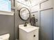 Stylish half bath with gray wainscoting, round mirror, and modern fixtures at 1941 Bright Kannon Way, Wendell, NC 27591