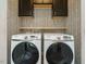 Well-organized laundry area featuring modern machines, stylish wallpaper, and convenient storage solutions at 1941 Bright Kannon Way, Wendell, NC 27591
