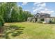 Expansive backyard with a large lawn area, mature trees, and the rear elevation of the house at 2016 Falls Forest Dr, Raleigh, NC 27615