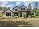 A backyard featuring a covered patio with an outdoor kitchen, fireplace, and beautifully landscaped lawn at 2016 Falls Forest Dr, Raleigh, NC 27615