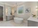 Bright bathroom features a soaking tub, double vanity, framed mirror, and modern light fixtures at 2016 Falls Forest Dr, Raleigh, NC 27615