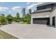 Spacious concrete driveway leading to a two-car garage with black doors, surrounded by green trees at 2016 Falls Forest Dr, Raleigh, NC 27615