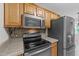 Close-up of the kitchen with stainless steel appliances, wooden cabinets, and granite countertops at 205 Smiths Creek Dr, Clayton, NC 27520