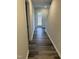 Hallway with dark wood-look floors leading to a white door with view of wooded area at 2118 Terrawood Dr, Durham, NC 27703