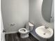 A well-lit powder room offers a pedestal sink, round mirror, and modern commode at 2118 Terrawood Dr, Durham, NC 27703