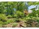 Lush backyard features mature trees, green foliage, and plant boxes, creating a serene landscape at 2143 Ridge Rd, Raleigh, NC 27607